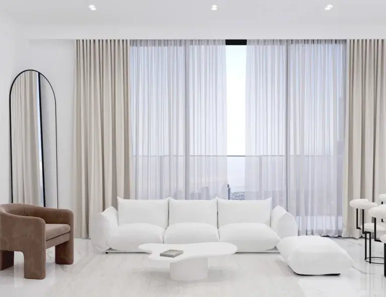 "Modern minimalist living room with white sofa, beige curtains, brown armchair, and city view through large glass windows